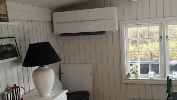 Indendørs varmepumpe i lyst træbeklædt rum.
